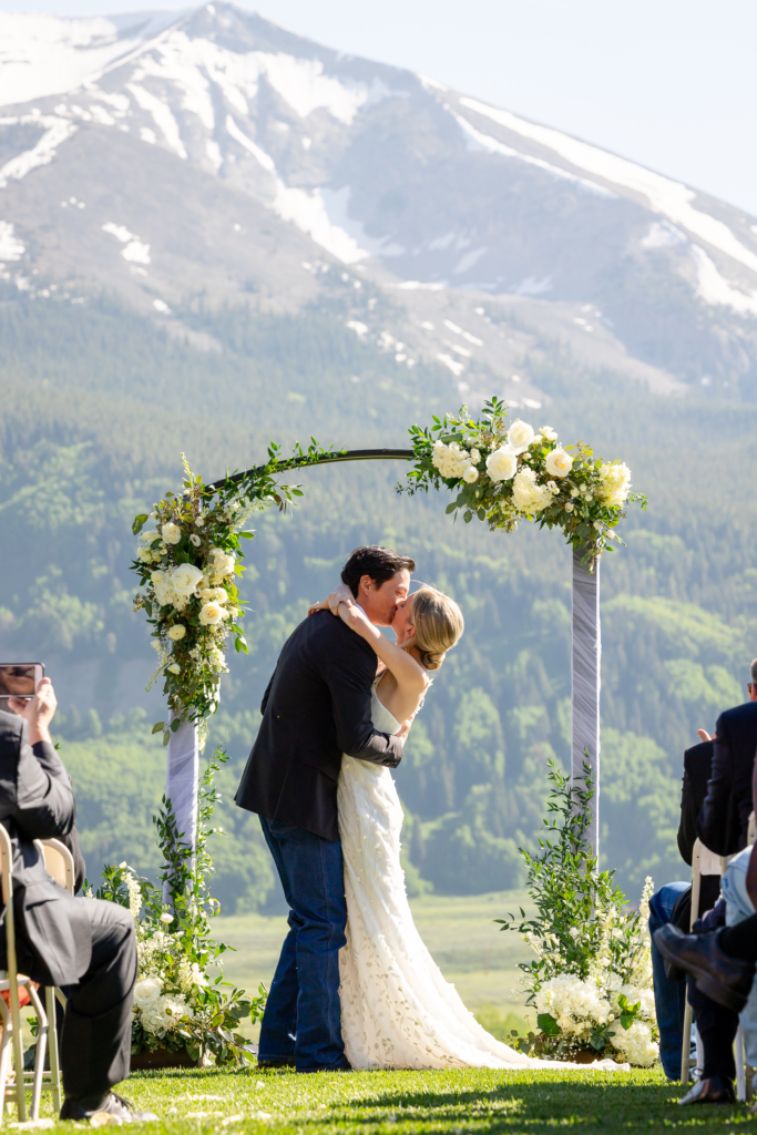 married couple kissing under arch at the Club at Crested Butte wedding venue