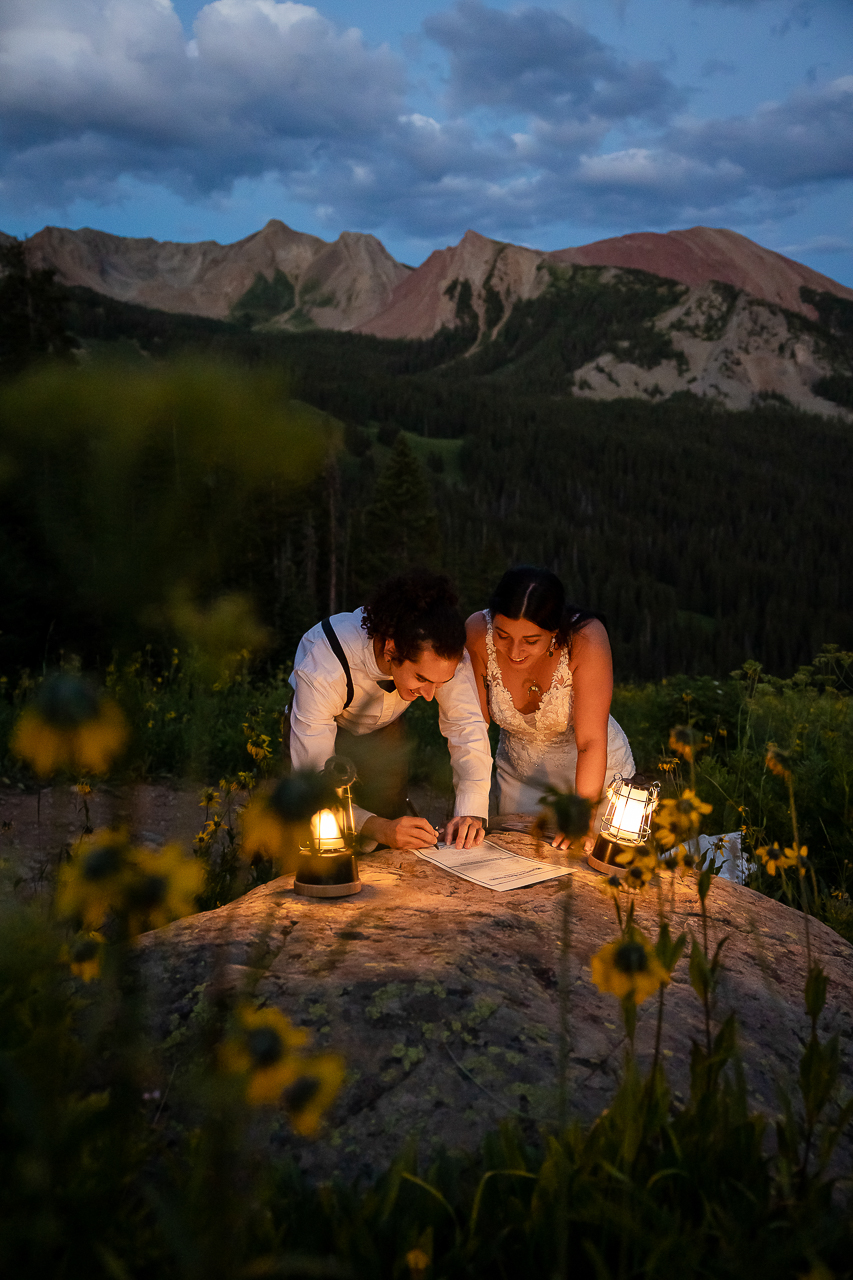 couple signing marriage license on rock in dark with lanterns and sunflowers Crested Butte photographer Gunnison photographers Colorado photography - proposal engagement elopement wedding venue - photo by Mountain Magic Media