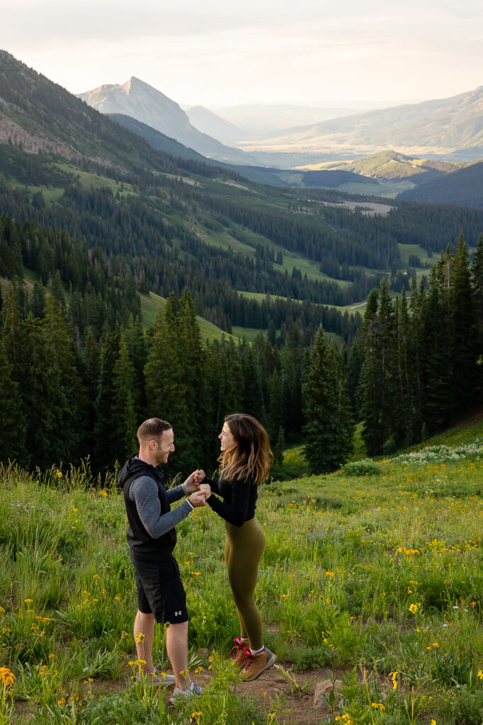 jumping in the air with excitement surprise proposal on one knee mountains background Crested Butte photographer Gunnison photographers Colorado photography - proposal engagement elopement wedding venue - photo by Mountain Magic Media