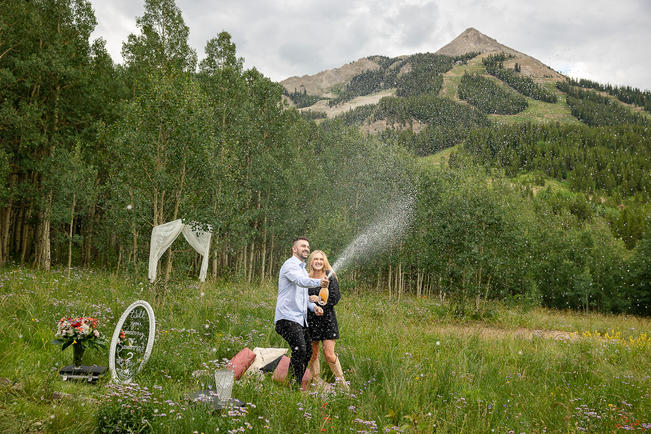 spraying champagne engaged will you marry me sign custom signage for surprise proposals mirror floral bouquet flowers champagne Crested Butte photographer Gunnison photographers Colorado photography - proposal engagement elopement wedding venue - photo by Mountain Magic Media