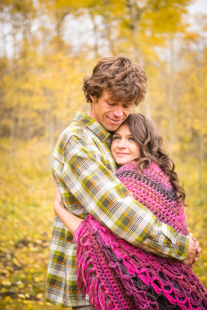 wrapped in blanket couple fall leaves About Us Bio Lydia + T anniversary - photo by Mountain Magic Media - Colorado Photographer Team Travel Photographers