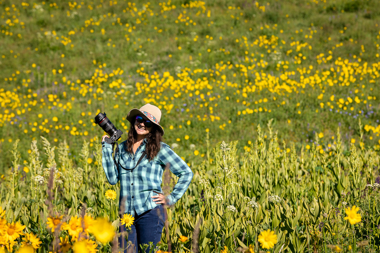 holding camera in wildflowers field Crested Butte photographer Gunnison photographers Colorado photography - proposal engagement elopement wedding venue - photo by Mountain Magic Media