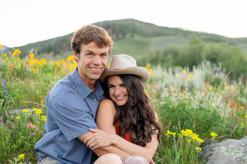 smiling couple arms wrapped around each other About Us Bio Lydia + T anniversary photo by Mountain Magic Media - Colorado Photographer Team Travel Photographers
