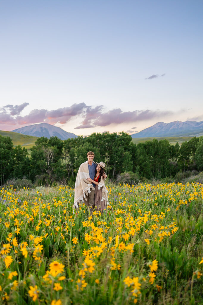 wrapped in blanket couple in flower fields wildflowers wildflower festival sunflowers About Us Bio Lydia + T anniversary 3 years - photo by Mountain Magic Media - Colorado Photographer Team Travel Photographers