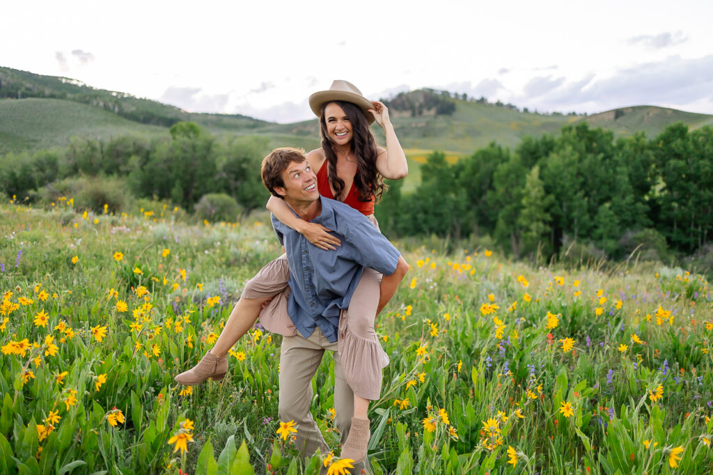 smiling couple piggyback About Us Bio Lydia + T anniversary photo by Mountain Magic Media - Colorado Photographer Team Travel Photographers