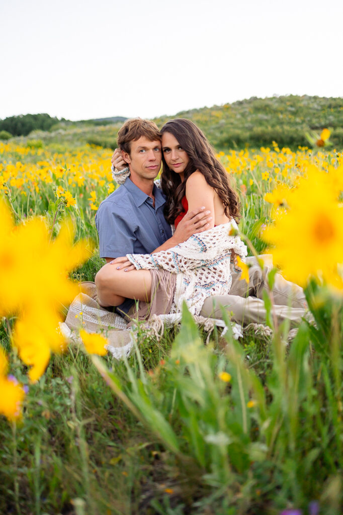 couple sitting in yellow sunflower wildflowers in Gunnison Colorado