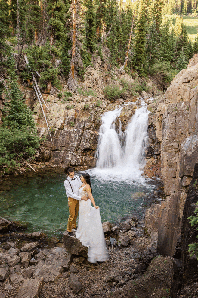 elopement adventure photography couple waterfall bride holding dress Crested Butte couple Colorado photographer wedding photographers