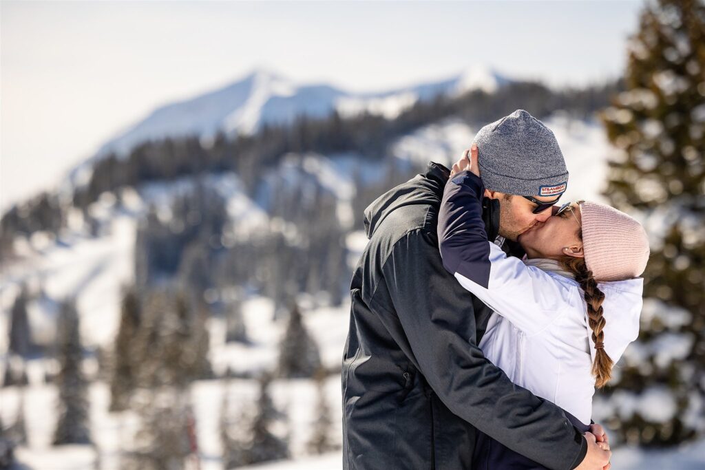 A couple kisses on a snowy mountaintop Colorado Proposal Photographer