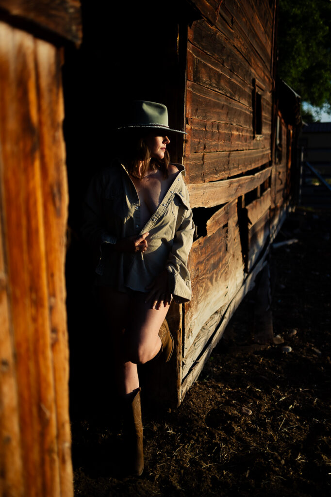 outdoor boudoir session woman leaning against the barnwood next to a barn in Gunnison, CO