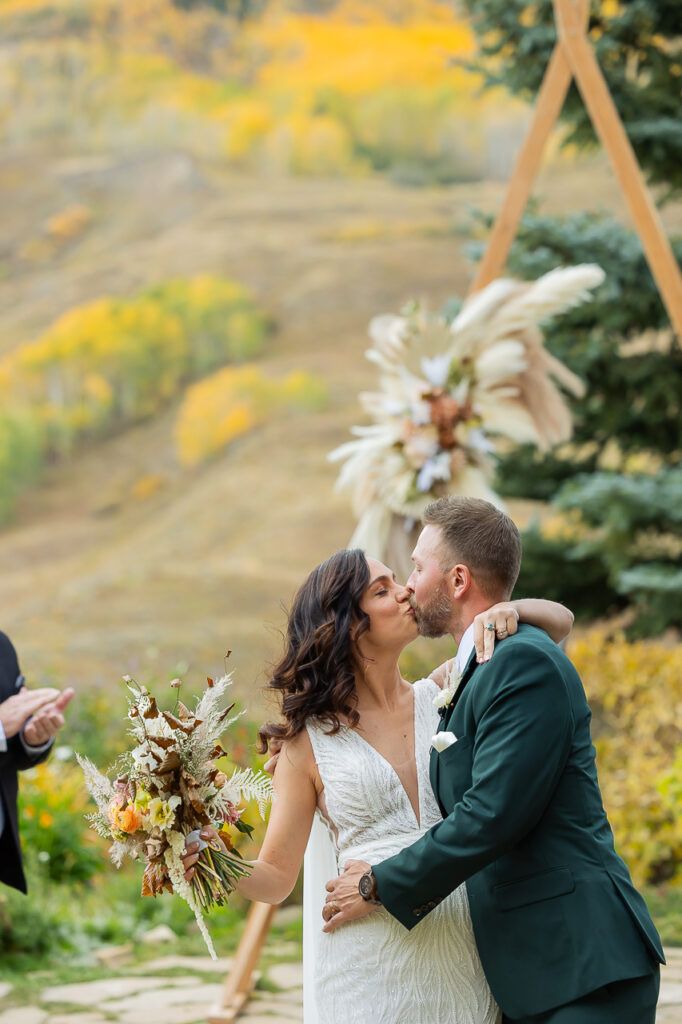 first kiss newlyweds couple just married wedding day Mountain Wedding Garden Crested Butte florals by Fin + Ally florist, plus planning and rentals by Lucky Penny Events