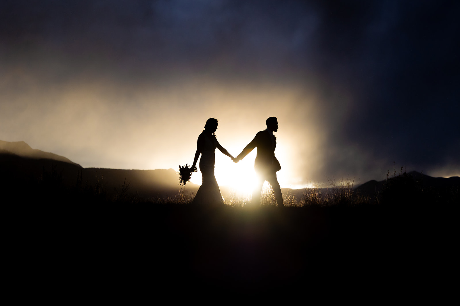 silhouette of wedding couple walking during sunset holding hands at the Mount Crested Butte Wedding Garden