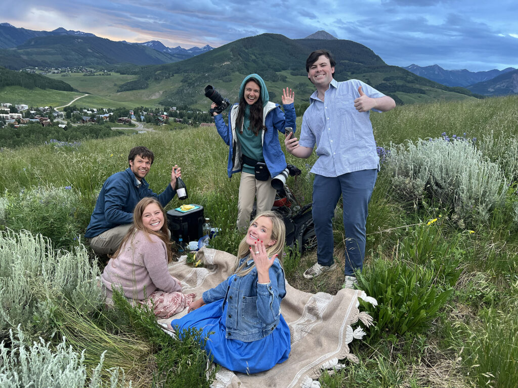 Couple celebrating engagement near Crested Butte Colorado at sunset with Mountain Magic Media local photographers man proposing to woman after a hike in Crested Butte surrounded by wildflowers with custom sign and florals for Proposal Packages